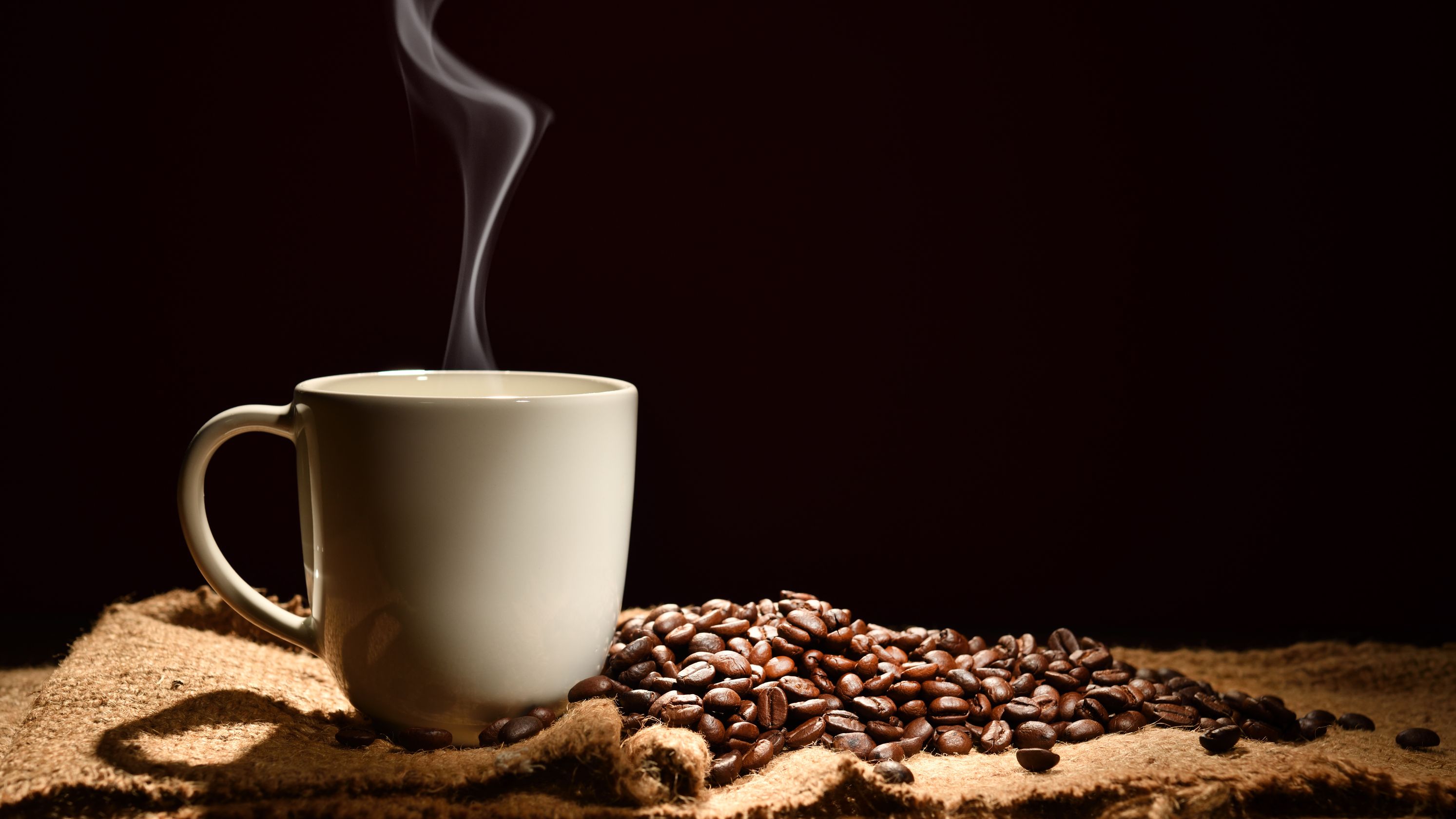 Кружка кофе кофеин. Кофе. Кофейный фон. Чашка кофе. Кофе на темном фоне.